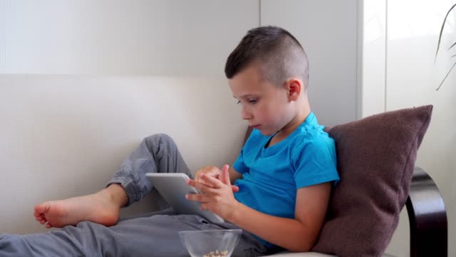 Süsser-Boy-entspannend-während-mit-Tablet-auf-sofa