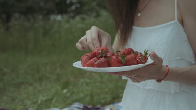 Fröhliche-Frau-Erdbeere-auf-Picknick-Essen