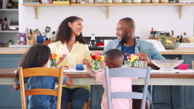Familia-Black-de-cuatro-hablando-durante-la-comida-en-su-cocina
