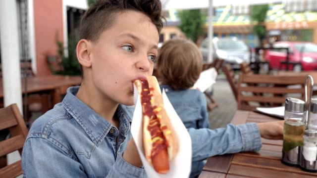 8-Jahre-alter-Junge-in-Jeanshemd-Essen-Leckere-Hot-Dog.