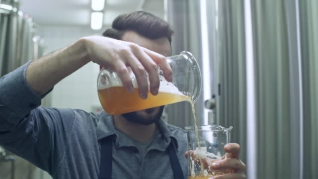 Maestro-cervecero-de-medición-cerveza-y-mirando-la-jarra