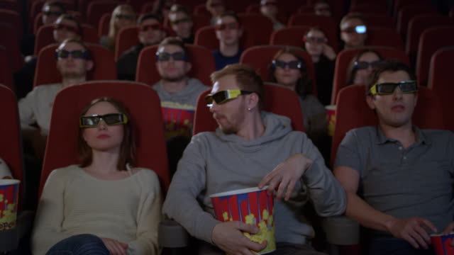Junge-Leute-sitzen-im-Kino-3D-Film-und-Essen-popcorn