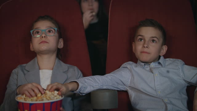 Los-niños-comen-palomitas-en-el-cine.-Niños-viendo-la-película-en-el-cine