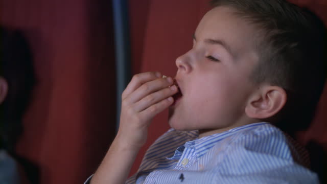 Niño-comiendo-palomitas-en-el-cine.-Adolescente-disfrutar-cine-comida
