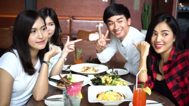Jóvenes-asiáticos-tomar-selfie-fotos-y-almorzar-juntos-en-el-restaurante-mientras-cambian-de-poses