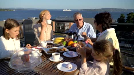 Eine-große,-glückliche-Familie-hat-Abendessen-auf-der-Terrasse-auf-dem-Dach-des-Hauses.