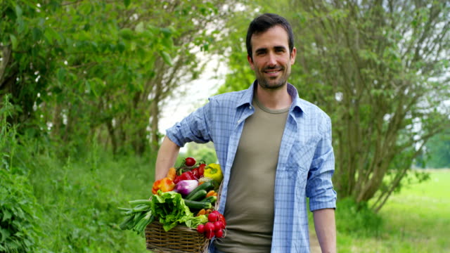 Porträt-eines-glücklichen-jungen-Landwirts-mit-frischem-Gemüse-in-einen-Korb.-Auf-Grund-der-Natur.