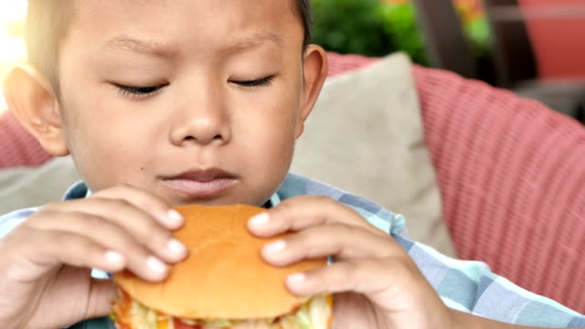 Lindo-muchacho-asiático-son-felices-comiendo-una-hamburguesa-en-restaurante.-Video-4k-lenta