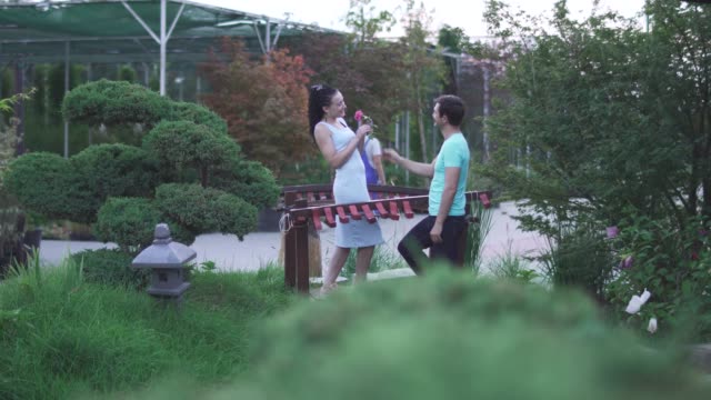 Adult-man-gives-flower-to-lady-in-the-garden