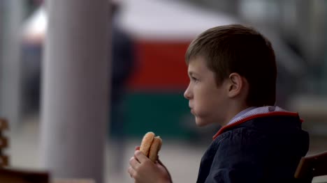 Junge-isst-einen-Burger-in-einem-Café-auf-der-Straße