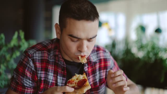 un-hombre-en-una-camisa-a-cuadros-es-comer-deliciosa-pizza-en-una-pizzería-en-la-tarde