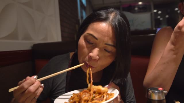 mujer-asiática-comiendo-fideos-con-palillos-en-un-restaurante