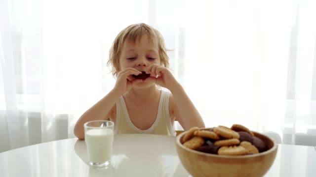 Junge-Essen-hausgemachte-Kekse-mit-Milch-in-der-Küche-zu-Hause.