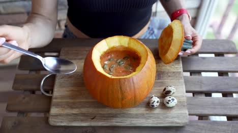 Happy-young-woman-eating-pumpkin-soup-in-kitchen