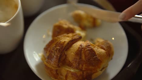 Close-up---the-hand-of-an-unidentified-woman-cuts-a-croissant-with-dessert-knife