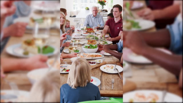 Bild-in-Bild-Aufnahme-der-großen-Gruppe-von-Freunden,-die-Tabelle-zu-Hause-herumsitzen-und-in-Zeitlupe-gedreht-genießen-Mahlzeit-zusammen-