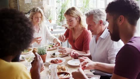 Eine-Multi-ethnische,-gemischte-Altersgruppe-der-Erwachsenen-Freunde-Tapas-zusammen-an-einem-Tisch-in-einem-Restaurant-Essen,-Nahaufnahme,-selektiven-Fokus