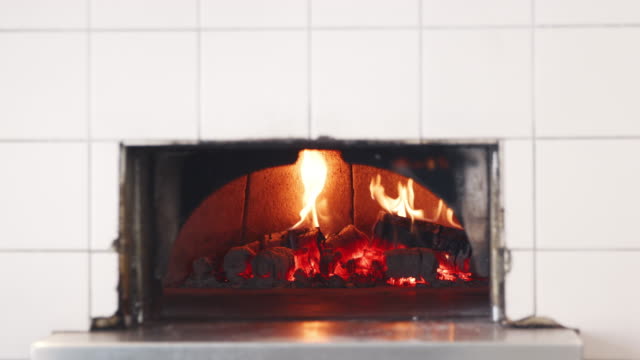 Flames-and-wood-burning-in-the-clay-oven-at-an-artisan-bakery,-close-up