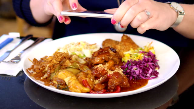 Woman-taking-picture-of-her-dinner-at-asian-reastaurant-in-4k-slow-motion-60fps