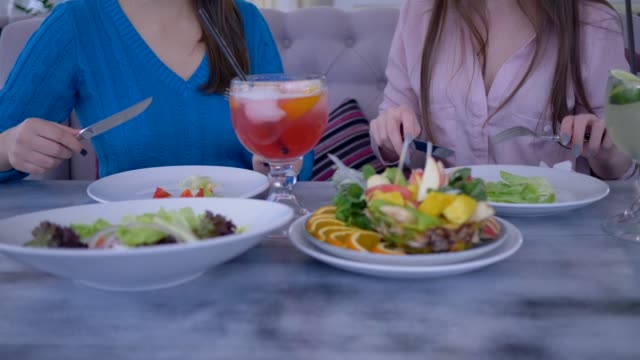 gesunde-Ernährung,-kommunizieren-junge-Frauen-bei-einem-Abendessen-am-Tisch-sitzen-und-Essen-griechischen-Salat-im-café