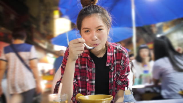 Junge-attraktive-Asiatin-Straße-Essen-auf-einem-Nachtmarkt-in-Thailand.-Thai-Food-Konzept.-Asian-Food-Konzept