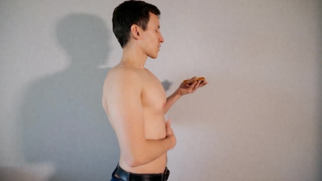 Junger-Mann-riecht-ein-Stück-Pizza-auf-grauem-Hintergrund