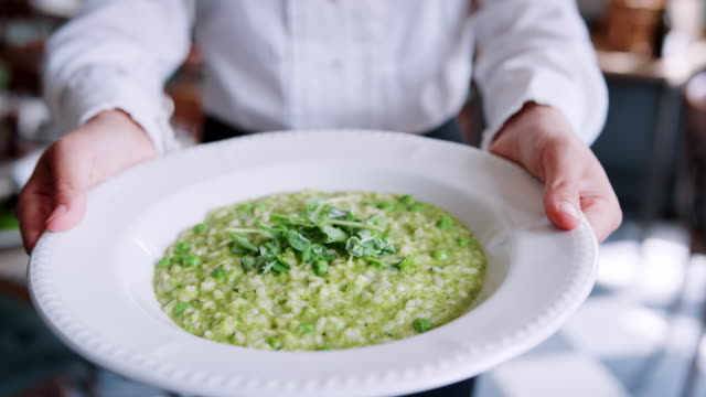 Close-Up-Of-Restaurant-Waitress-Holding-Plate-Of-Pea-Risotto
