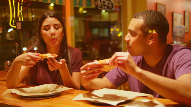 Una-joven-pareja-comiendo-en-un-centro-de-la-ciudad-de-pizzeria