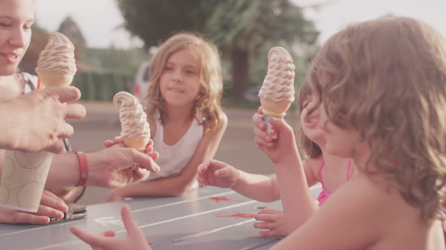 A-father-hands-out-ice-cream-cones-to-his-kids-at-a-picnic-table