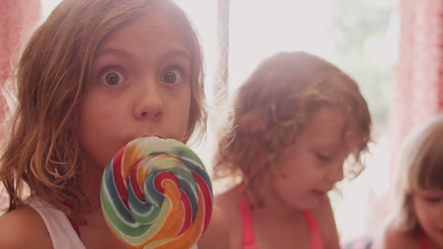 A-little-girl-eating-a-lollypop-and-then-eating-cookie-dough-with-her-sisters