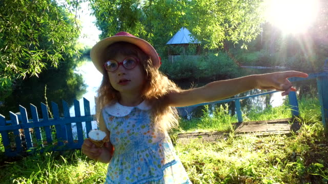 Kleines-Mädchen-mit-langen-Haaren-isst-Eis-im-Park.