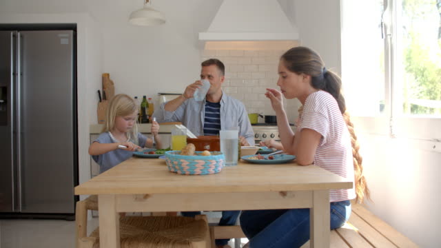 Familia-sentada-alrededor-de-la-mesa-de-la-cocina-comer-comida