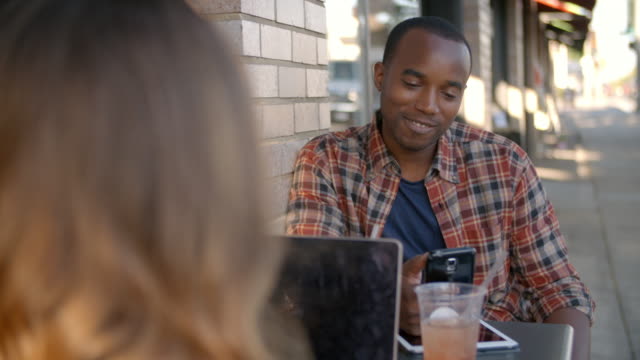 Mixed-race-couple-using-technology-outside-a-coffee-shop
