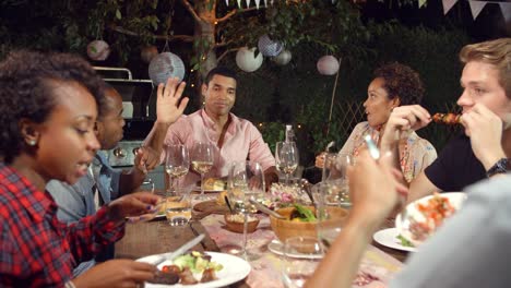 Jungen-Erwachsenen-Freunden-essen-und-trinken-zu-einem-Outdoor-Dinner-party