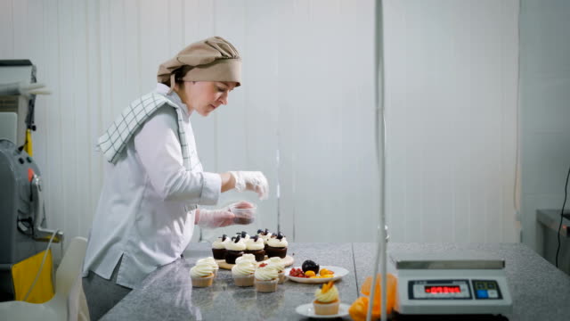 The-woman-cooks-cakes-for-a-holiday.-At-the-girl-the-order-as-the-candy-store-is-small-business.-Cakes-are-ready-on-a-table.-On-a-table-chocolate-and-fruit-cupcakes