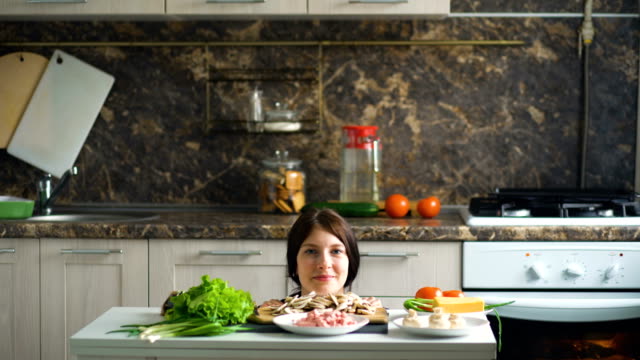 Retrato-de-hermosa-mujer-sonriente-cocina-mostrar-por-encima-de-la-mesa-con-verduras-en-la-cocina-en-casa