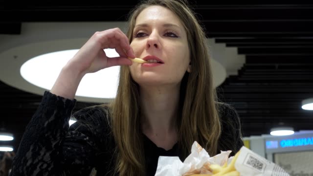 Junge-Frau-isst-Hamburger-und-Pommes-frites