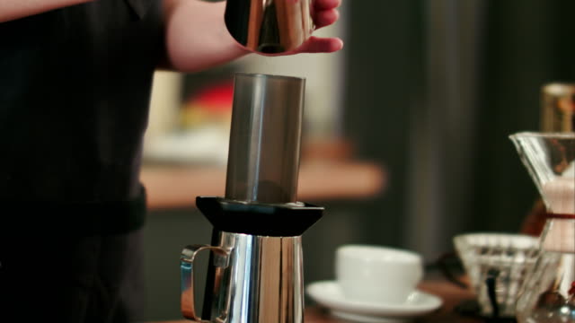 Barista-adding-grinded-coffee-and-pouring-hot-water