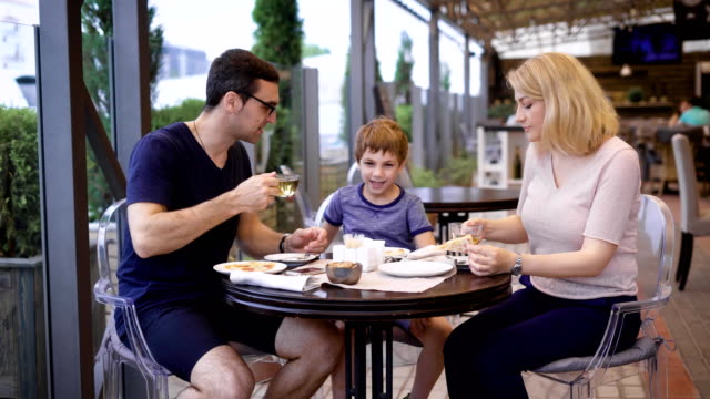 Family-is-enjoying-the-meal-all-together-in-the-restaurant,-laughing-and-chatting-with-each-other