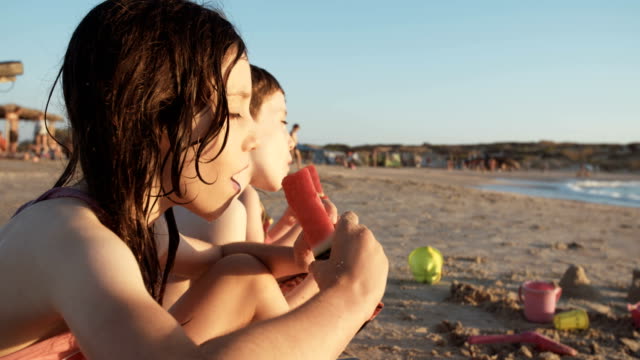 Drei-Kinder-essen-Wassermelonen-am-Strand
