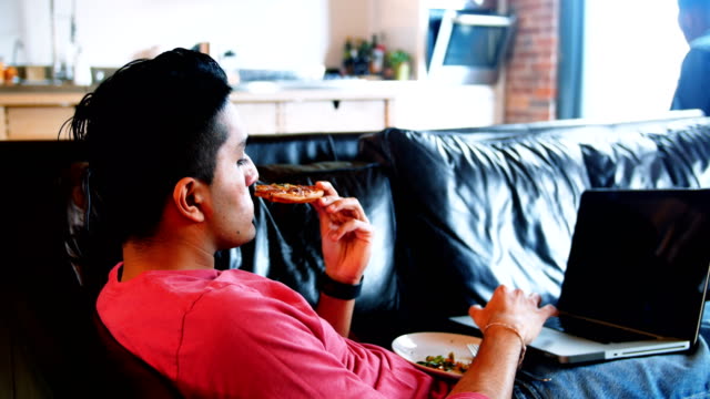 Menschen-essen-während-mit-Laptop-im-Wohnzimmer