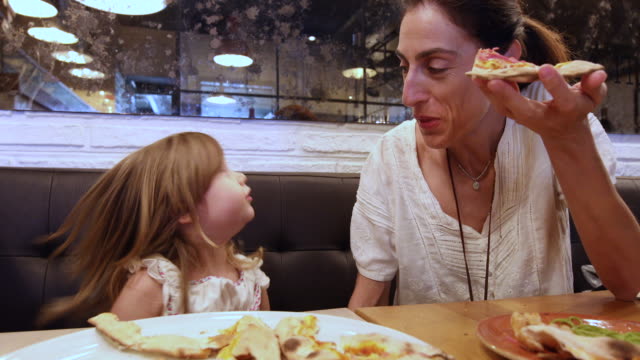 niña-y-la-madre-en-restaurante-comiendo-pizza