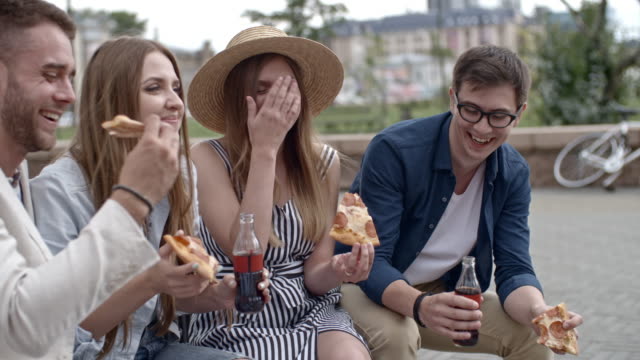 Amigos-comer-Pizza-con-Coca-cola-al-aire-libre