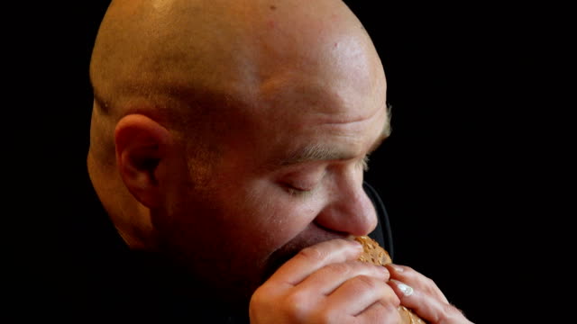 profile-of-bald--hungry-man-grabs-a-burger-voracious