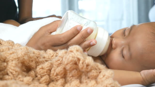 Muchacha-de-lindo-bebé-recién-nacido-durmiendo-y-chupando-botellas-de-leche