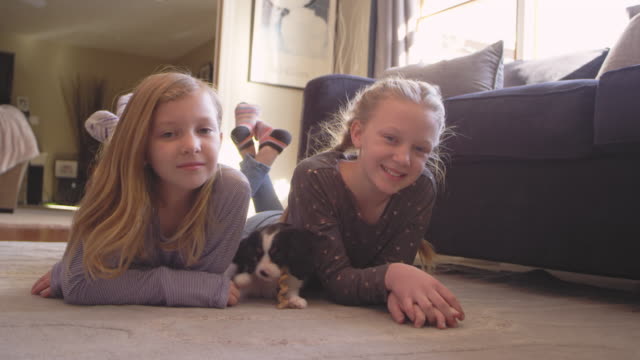 Portrait-of-two-young-girls-looking-at-the-camera,-while-their-adorable-puppy.