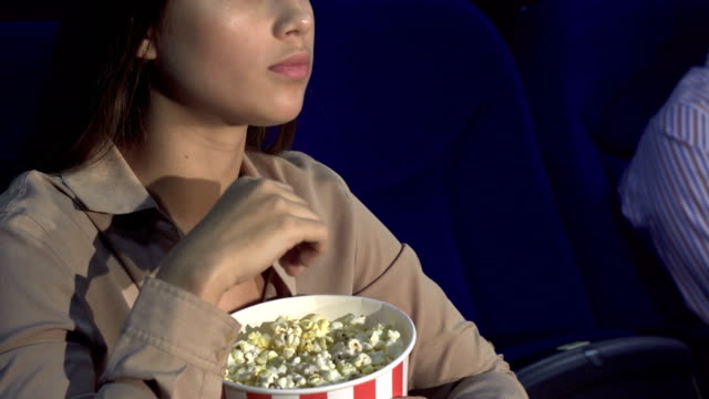 Eine-Nahaufnahme-der-wie-ein-Mädchen-isst-Popcorn-und-zeigt-ein-Zeichen-der-Stille