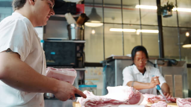 Three-butchers-preparing-meat-at-a-butcher's-shop
