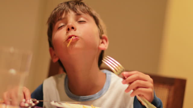 Komisch-übertrieben-Ausdrücken-des-jungen-Nudeln-zum-Abendessen-zu-genießen.-Expressive-Kind-essen-Spaghetti-Nudeln-zum-Abendessen.