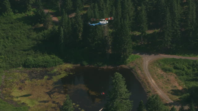 Aerial-shot-of-helicopter-getting-water-from-pond-to-fight-forest-fire.